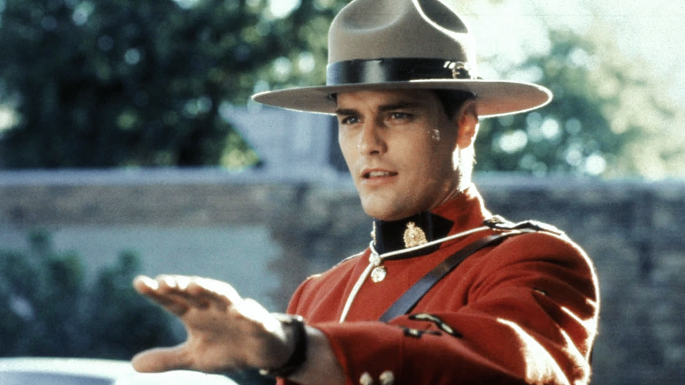 Benton Fraser in his bright red uniform and mountie hat, holding out his hand as if to say, Stop.